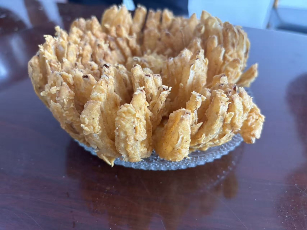 Original photograph of a golden coated whole onion blossom on a glass plate